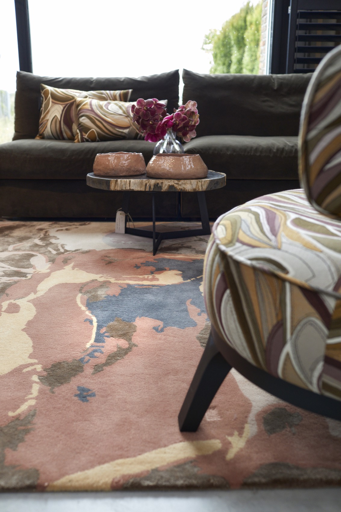 Vloerkleed in roze en blauwe tinten onder een fauteuil